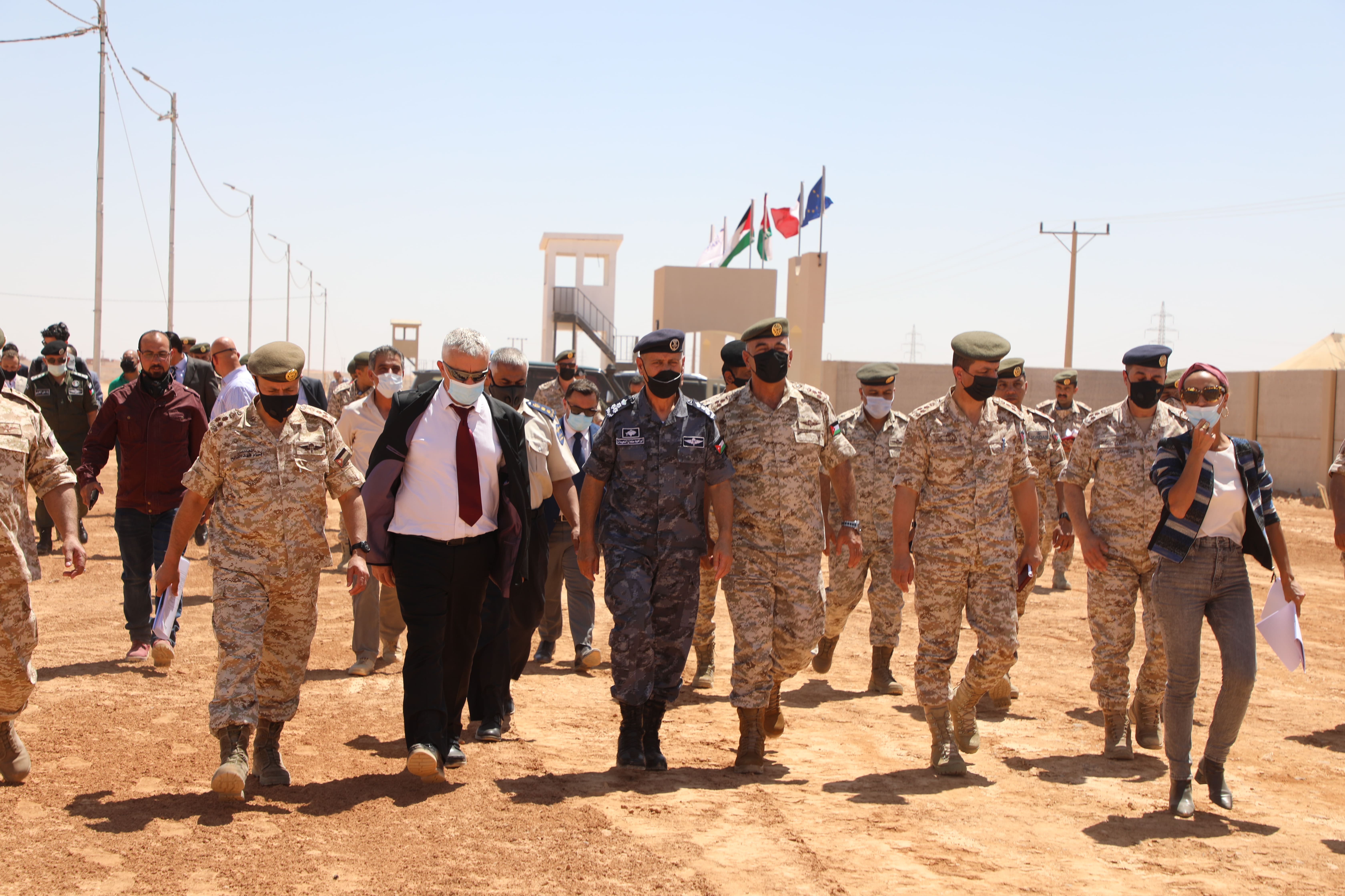 Groupe de personnes et militaires marchant.